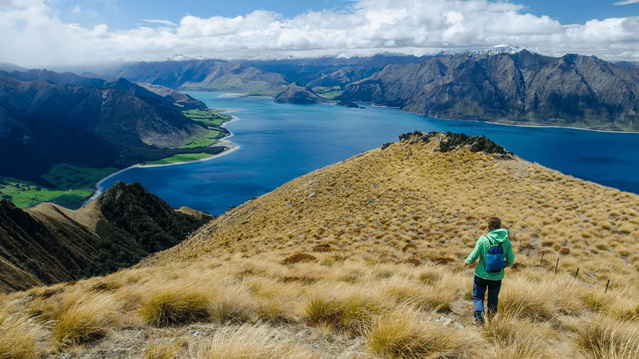 Vista panorâmica de montanha icônica da Nova Zelândia com lagos azuis e vales verdejantes, representando os diversos pontos turísticos do país"